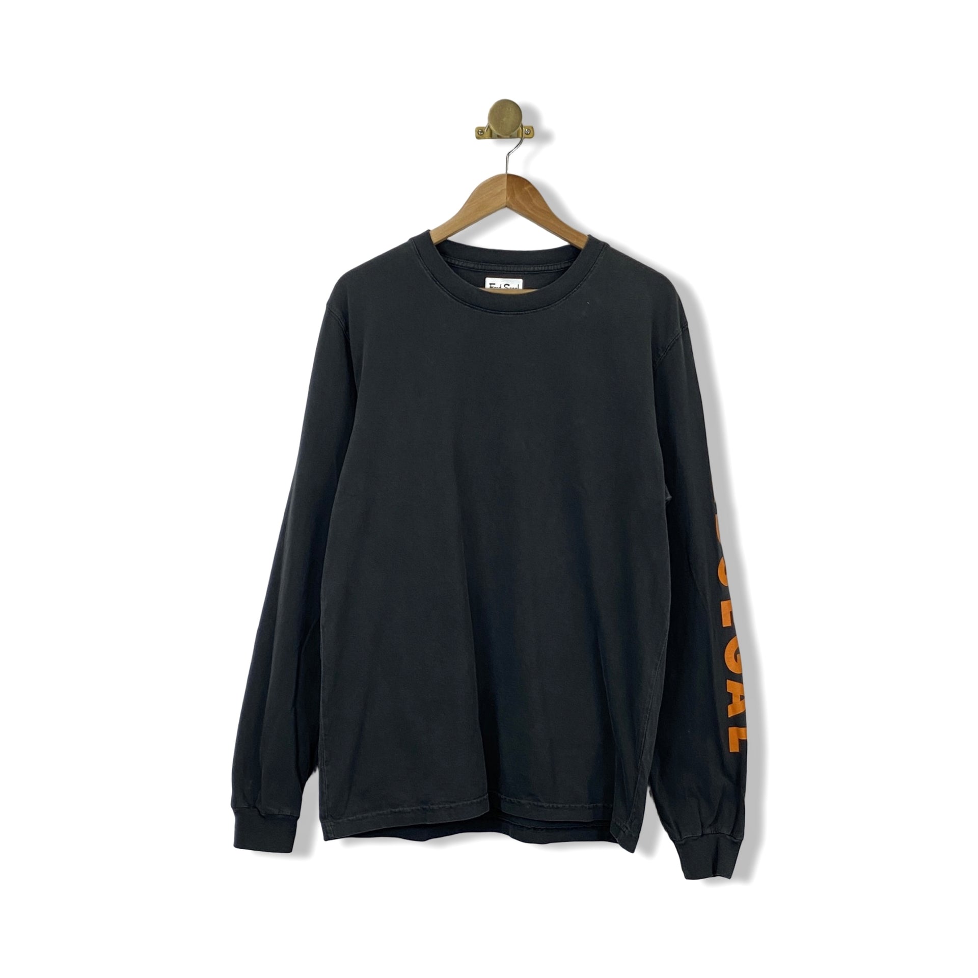 A long sleeve black t-shirt with orange text on the sleeves, displayed on a hanger against a white background.